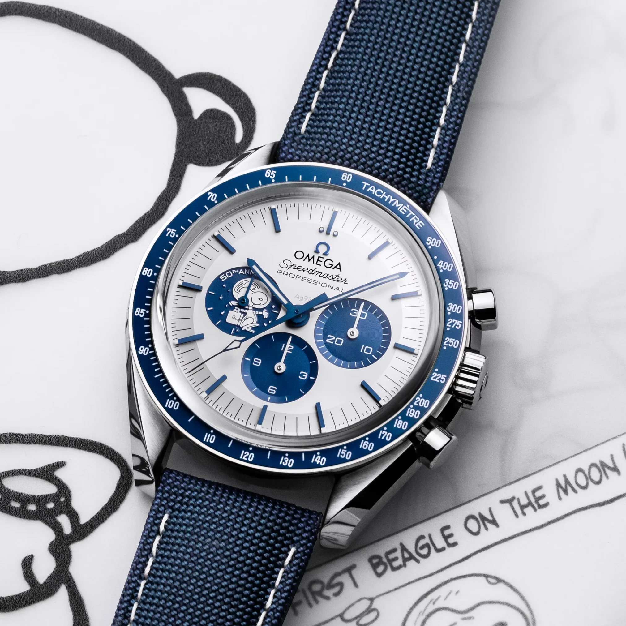 Đồng hồ Omega Speedmaster Anniversary Series "Silver Snoopy Award" Limited Edition 310.32.42.50.02.001 mặt số màu trắng xanh. Dây đeo bằng vải dù. Thân vỏ bằng thép.
